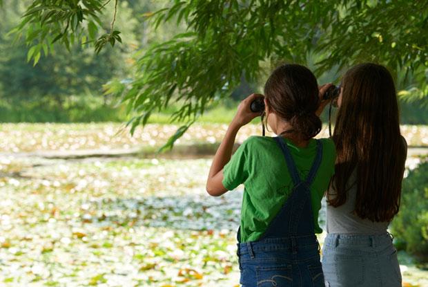 Two girls look at nature through binoculars at the Jardin Botanique de Montréal